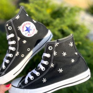 Une paire de baskets personnalisées couleur noir avec des marguerites