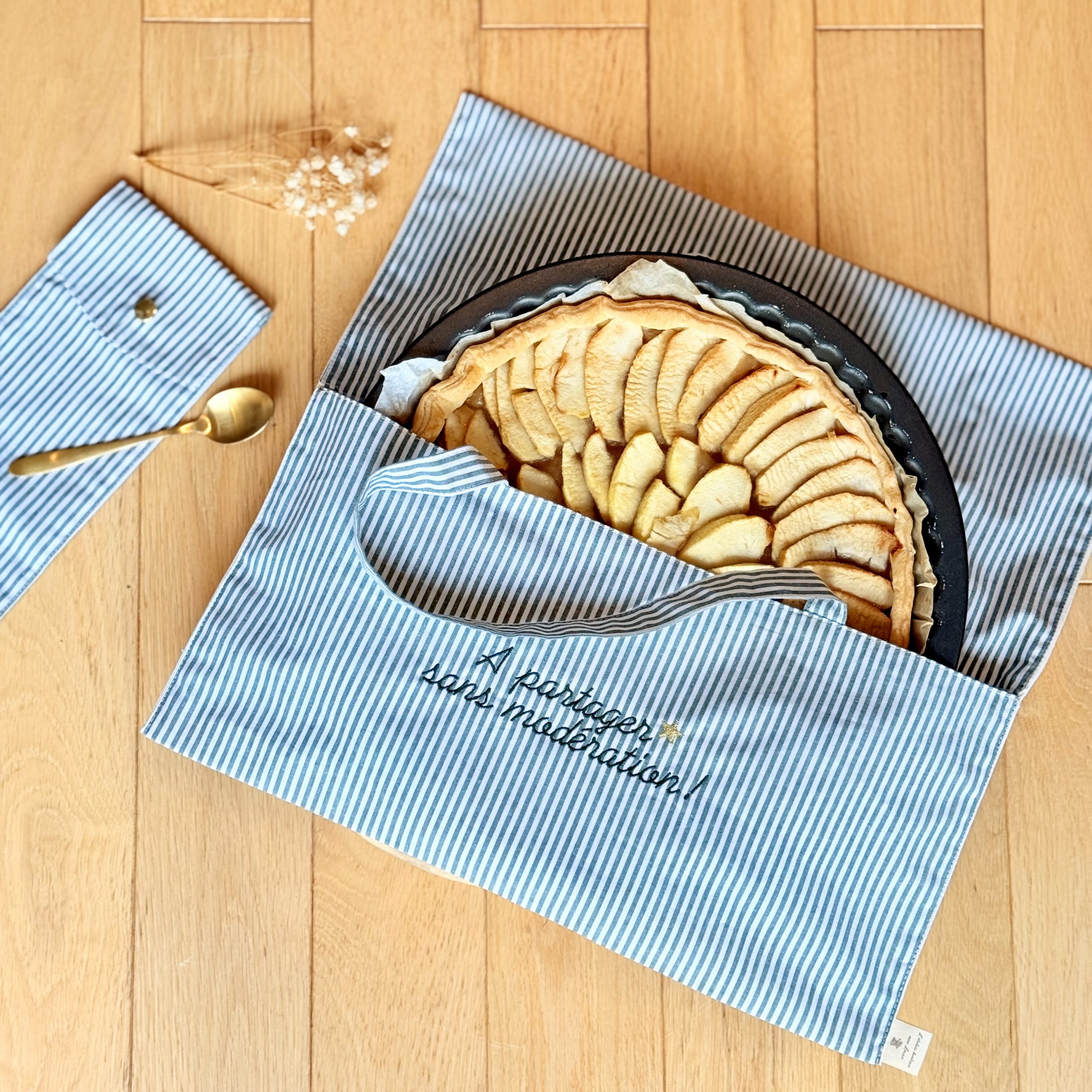 Sac à tarte personnalisé modèle rayures posé au sol avec une tarte aux pommes à l'intérieur